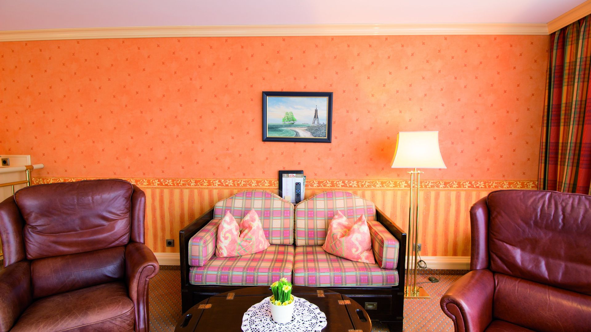 A living room with a couch , chairs , and a lamp.