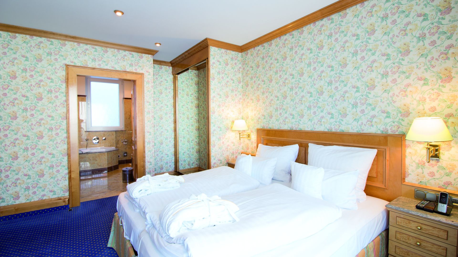 A hotel room with two beds , a nightstand and a bathroom.