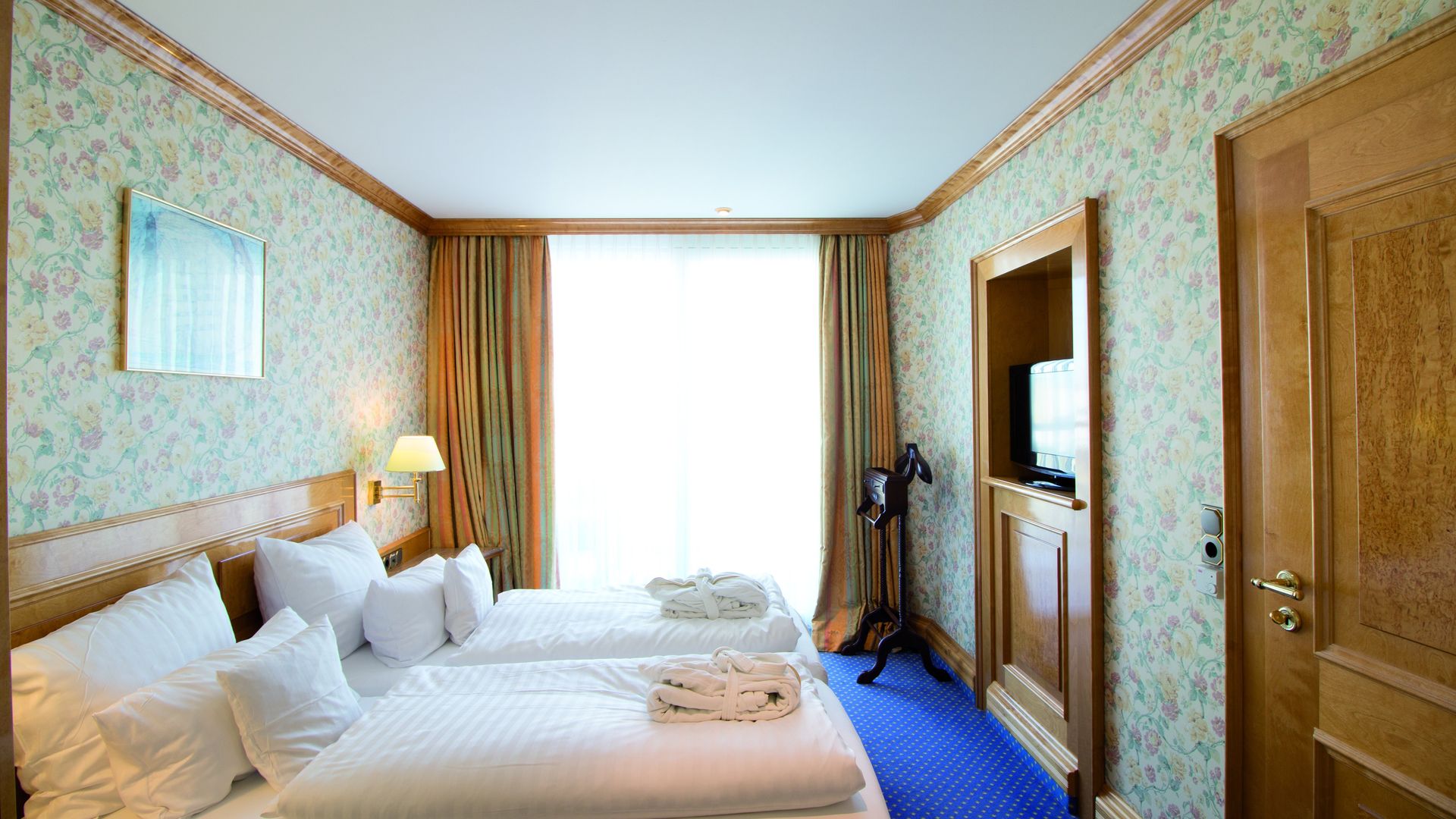 A hotel room with two beds and a television.
