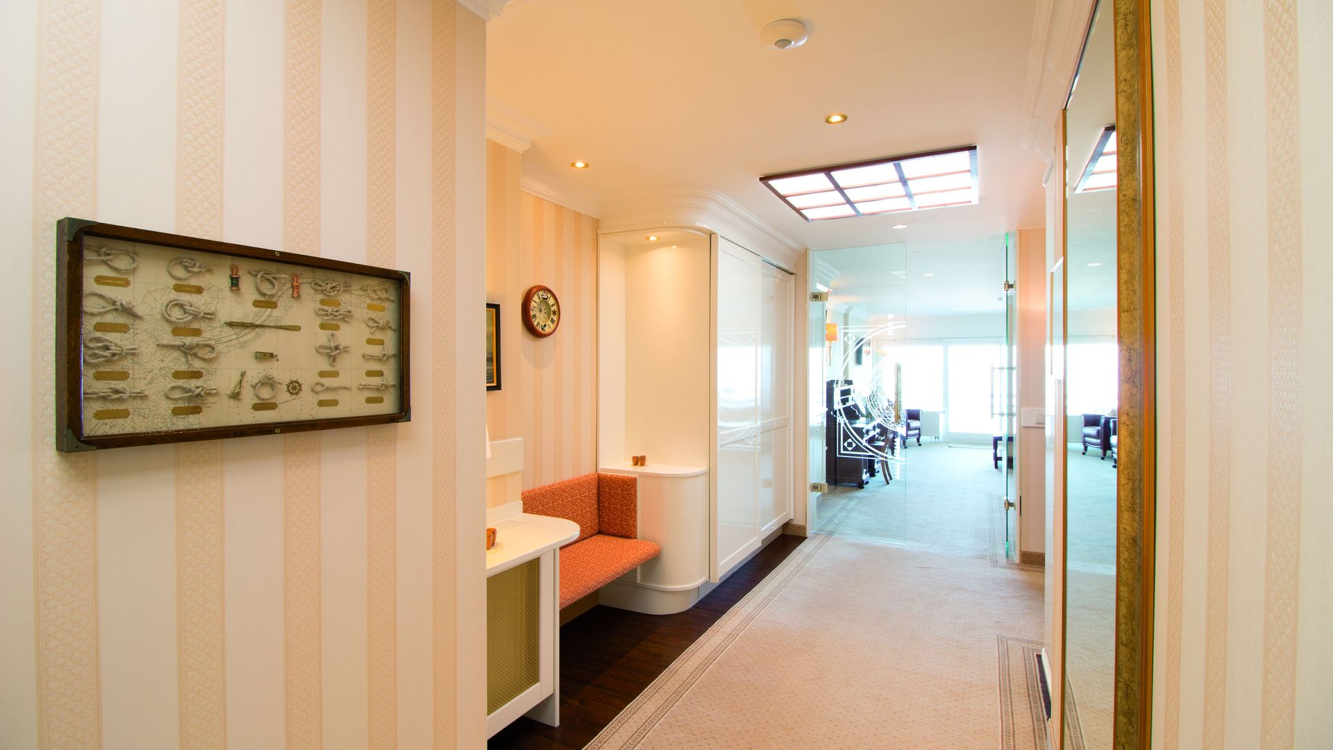 A long hallway with a bench and a clock on the wall.
