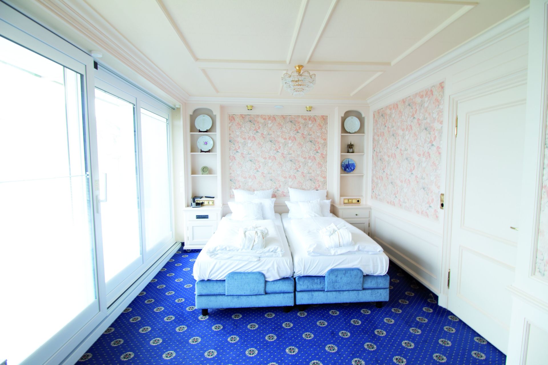 A hotel room with two beds and a blue carpet