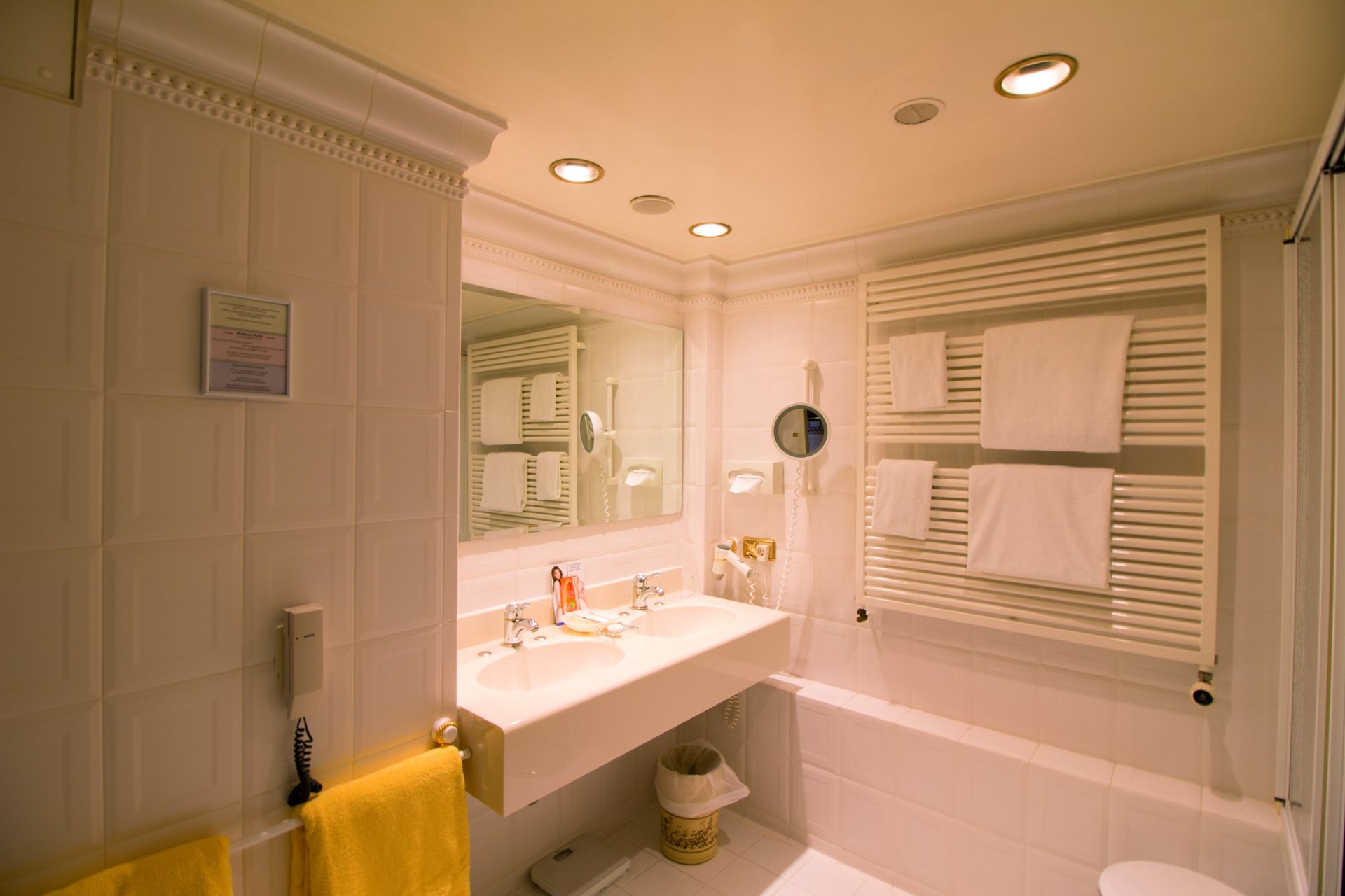 A bathroom with two sinks , a tub , a mirror and a towel rack.