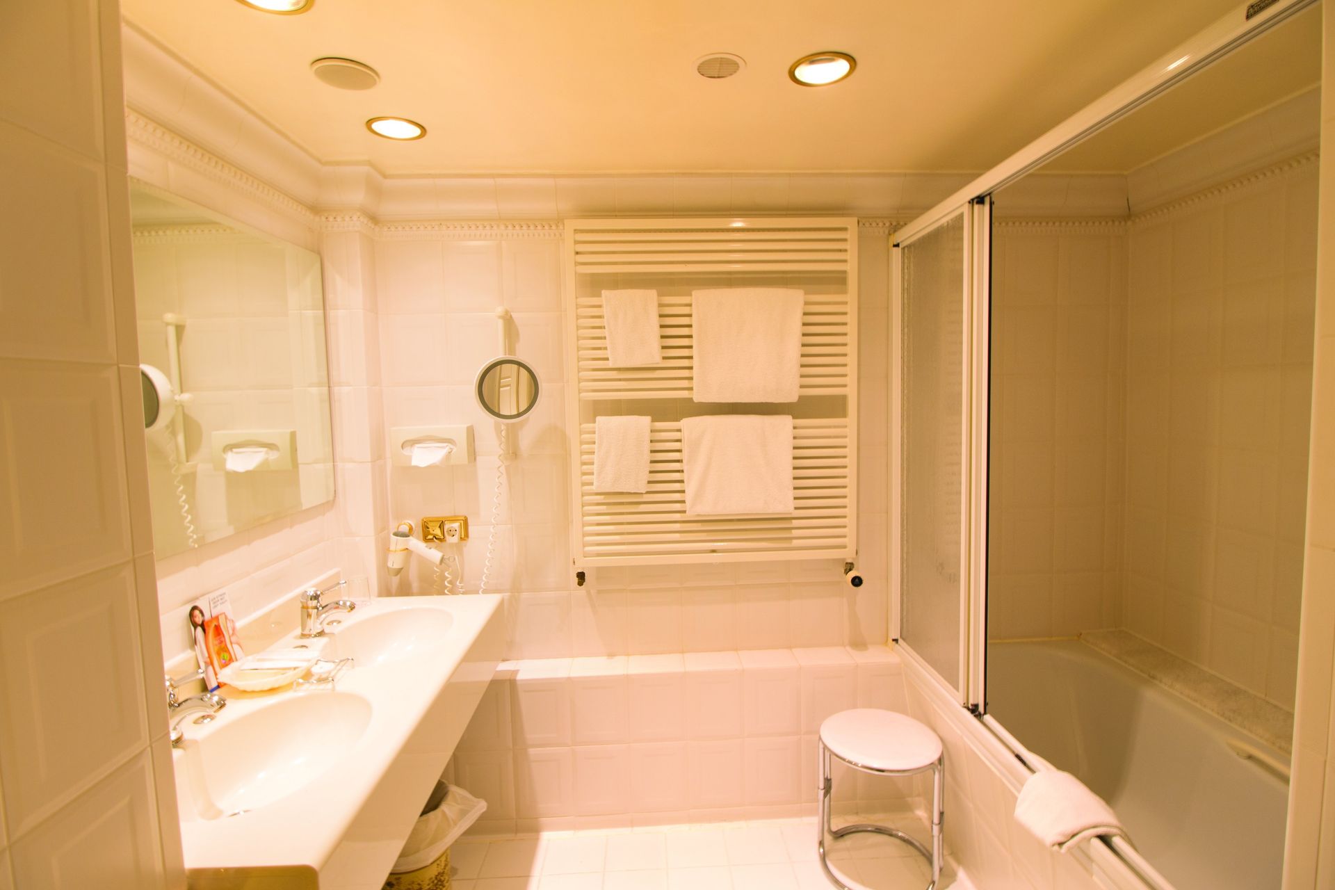 A bathroom with a tub , sink , mirror and towel rack
