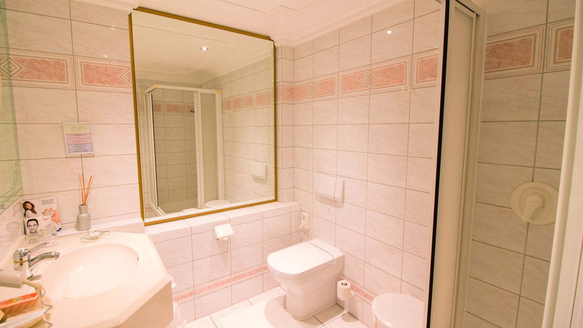 A bathroom with a toilet , sink , mirror and shower.
