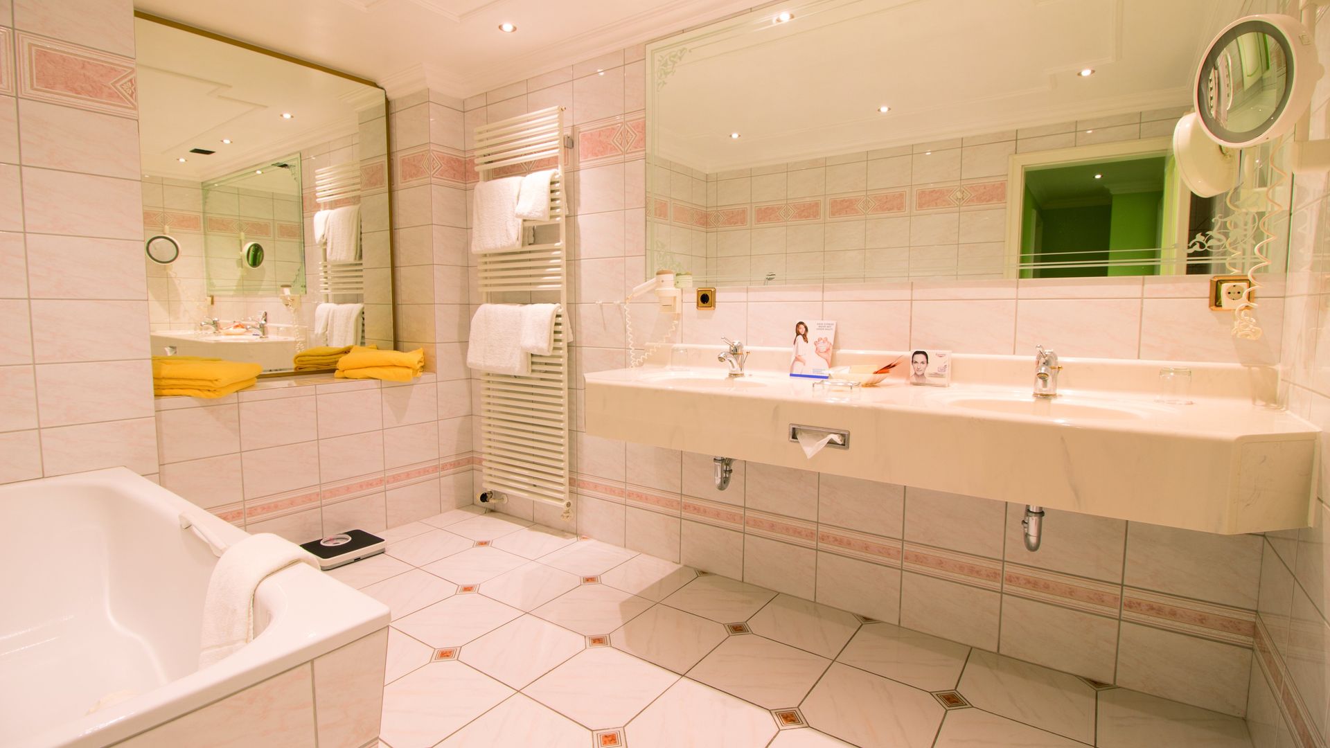 A bathroom with two sinks , a tub and a mirror.