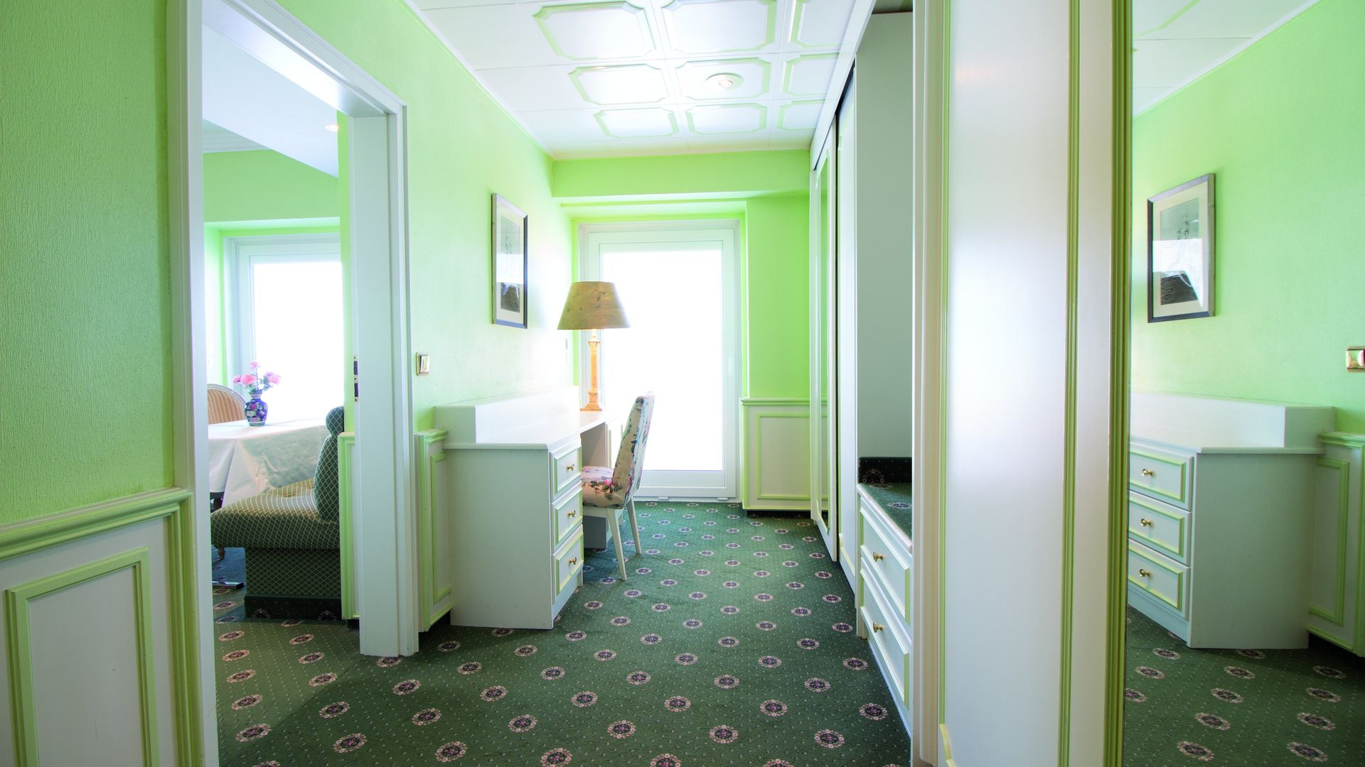 A hallway in a hotel room with green walls and a green carpet.