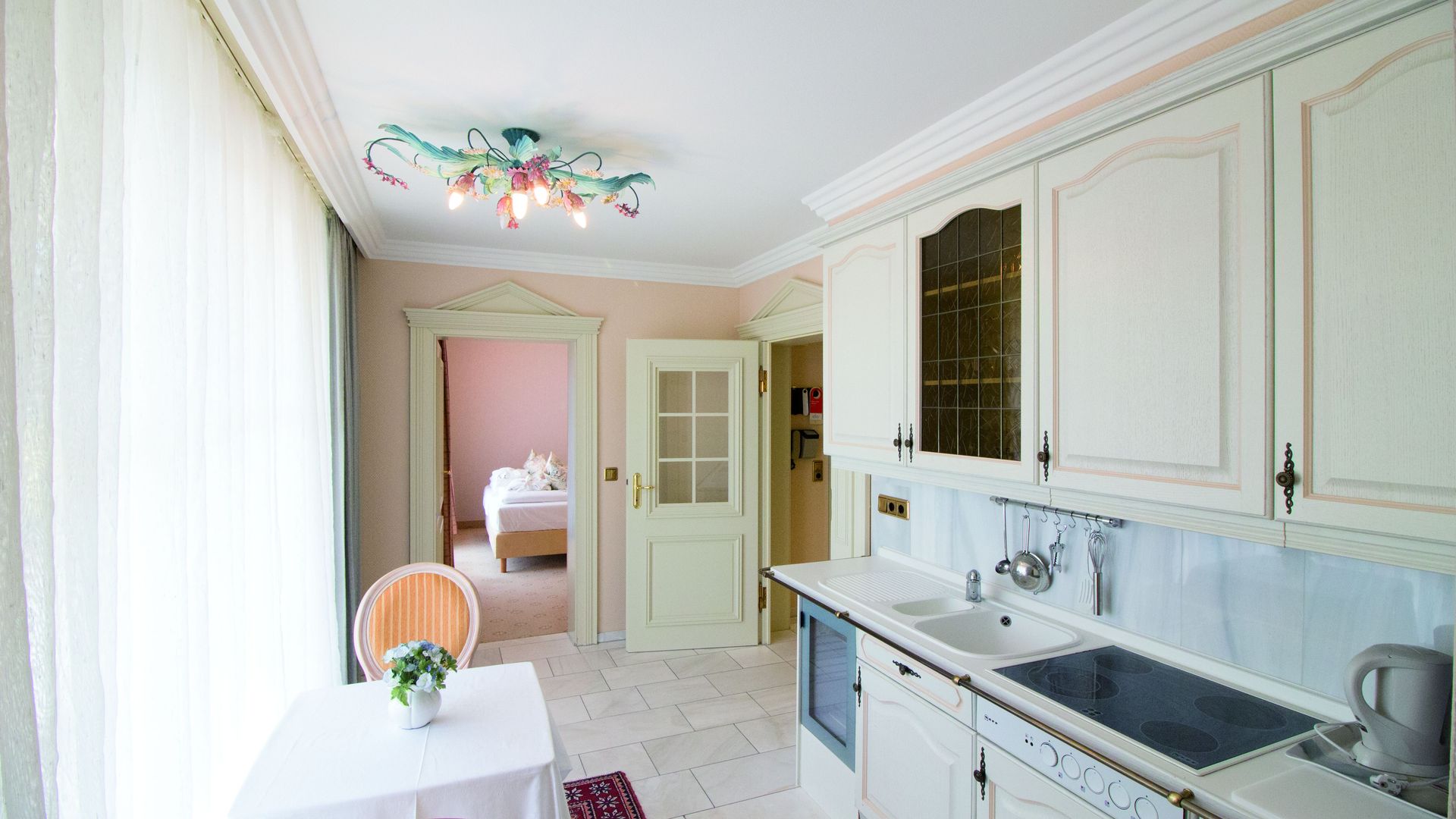 A kitchen with white cabinets , a stove , a sink , and a table.