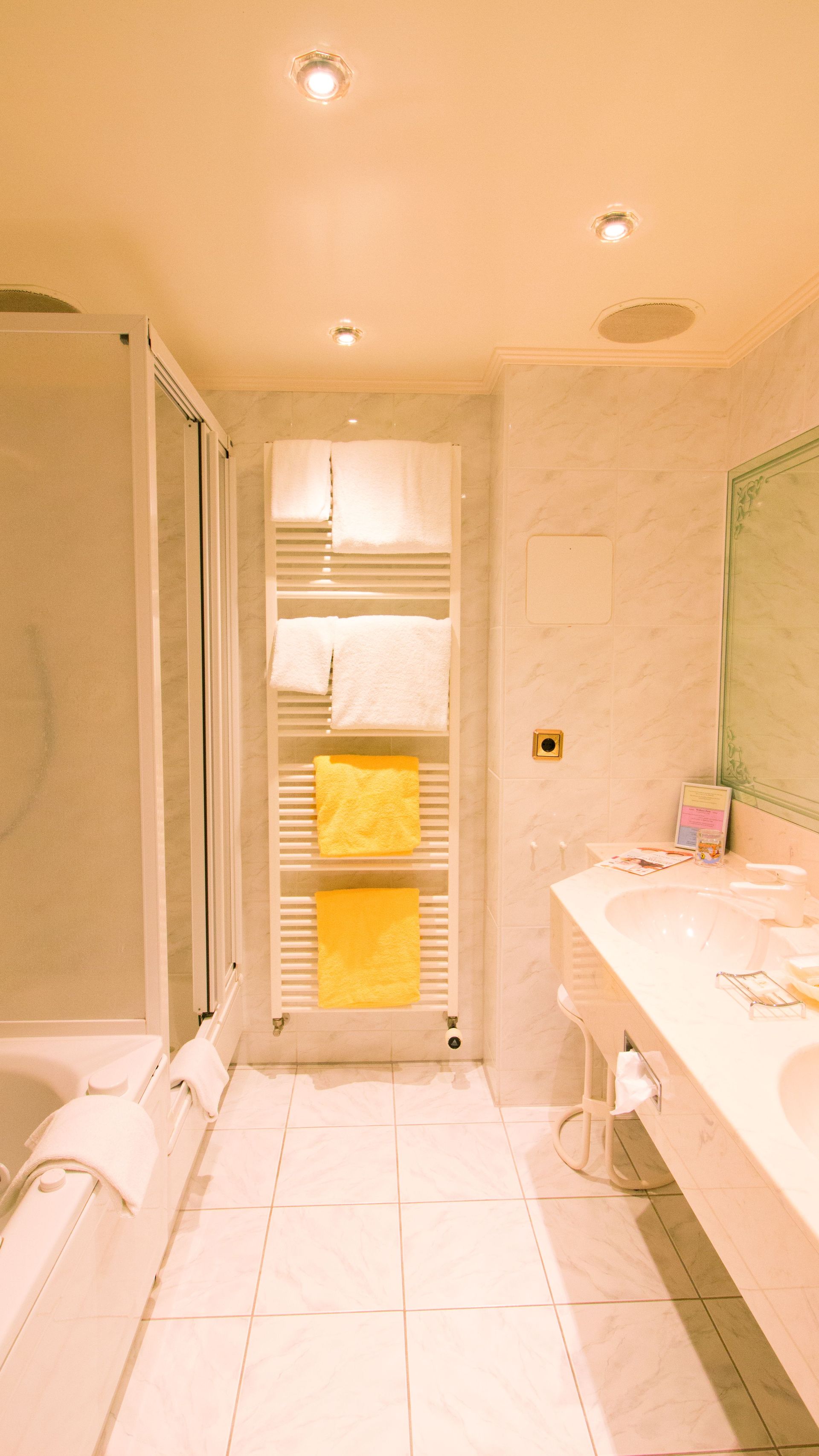 A bathroom with a shower , sink , and towel rack.