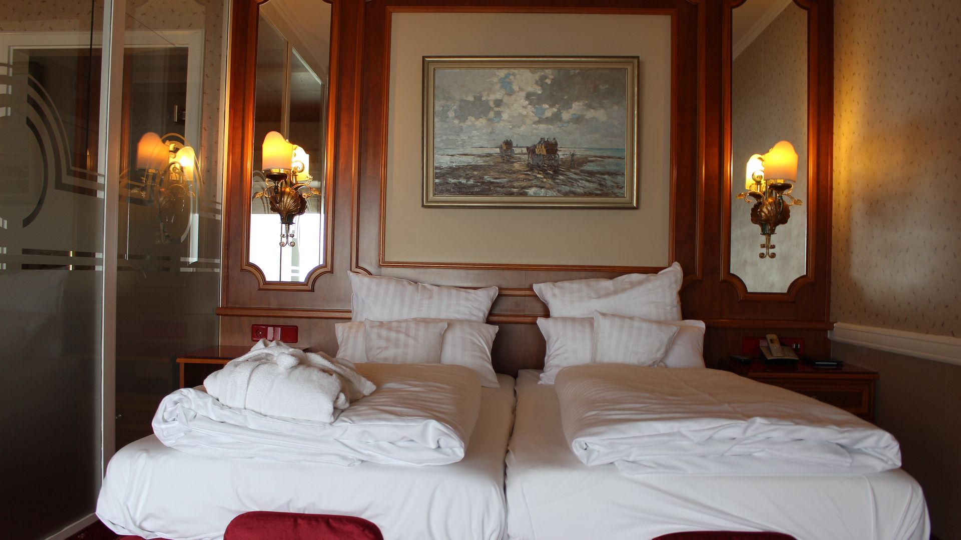 A hotel room with two beds and a painting on the wall.
