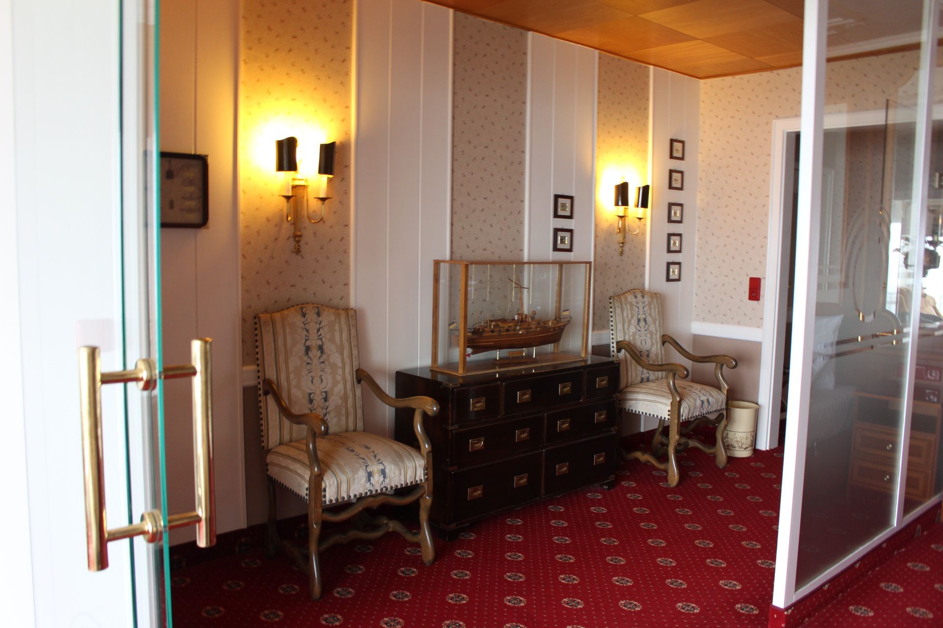 A room with a red carpet and chairs and a glass door