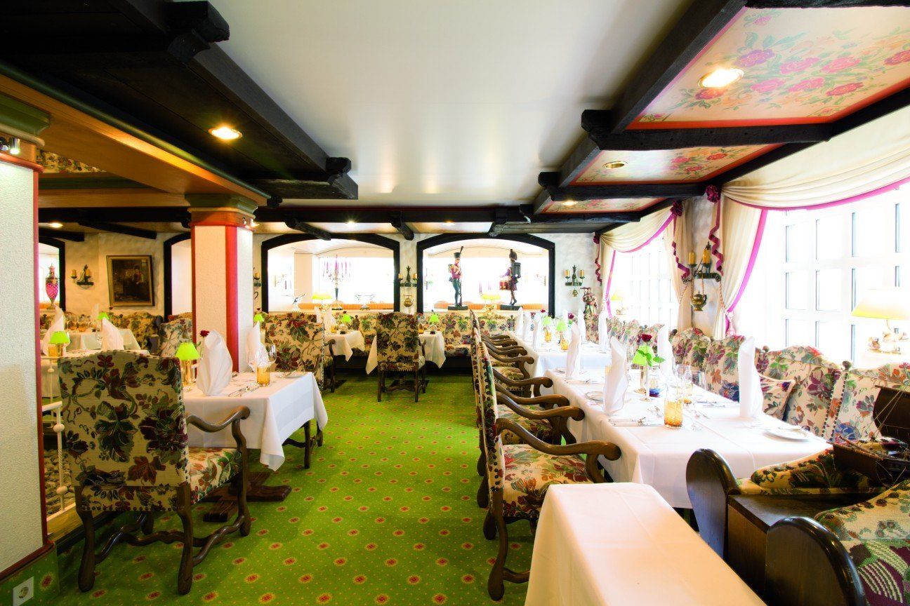 Ein Restaurant mit Tischen und Stühlen und einem grünen Teppich