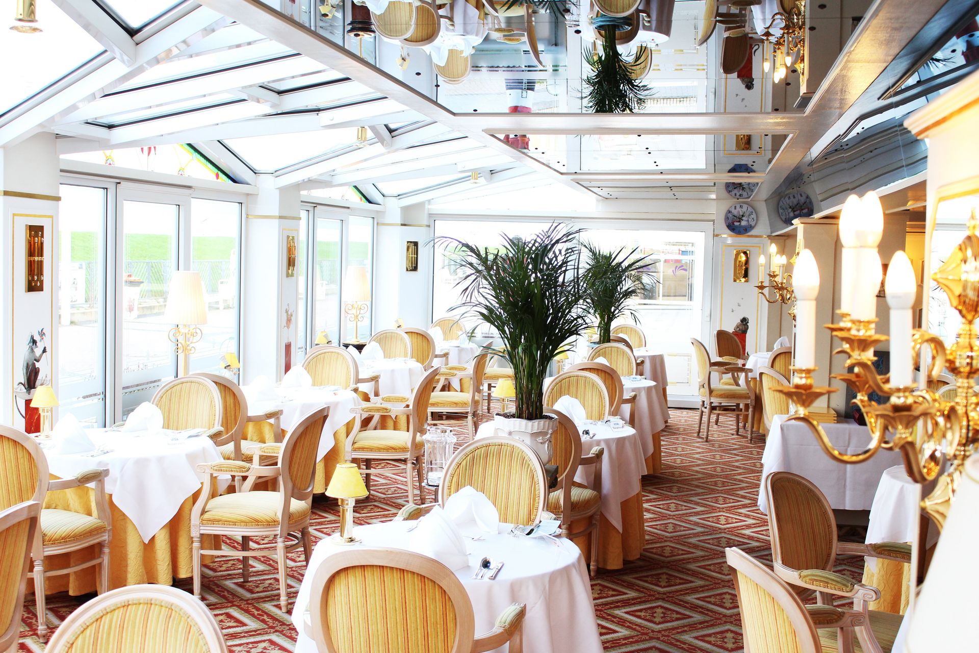A large dining room with tables and chairs and a mirrored ceiling.