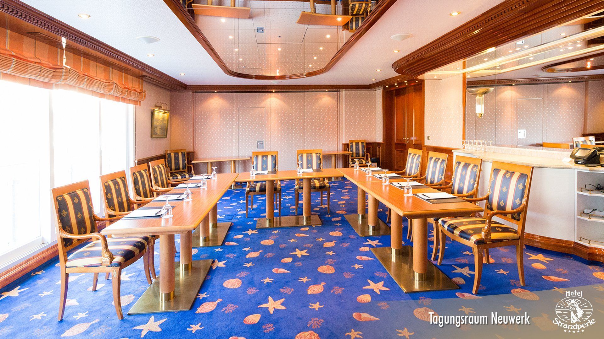 A conference room with tables and chairs and a blue carpet