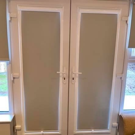 A pair of sliding glass doors with blinds in a living room.