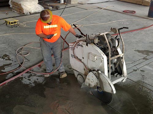 Worker watching while sawing concrete foundation - Concrete foundation sawing in Milton, WA