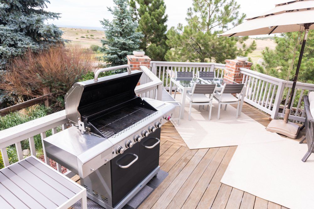 Un gril est posé sur une terrasse à côté d'une table et de chaises.