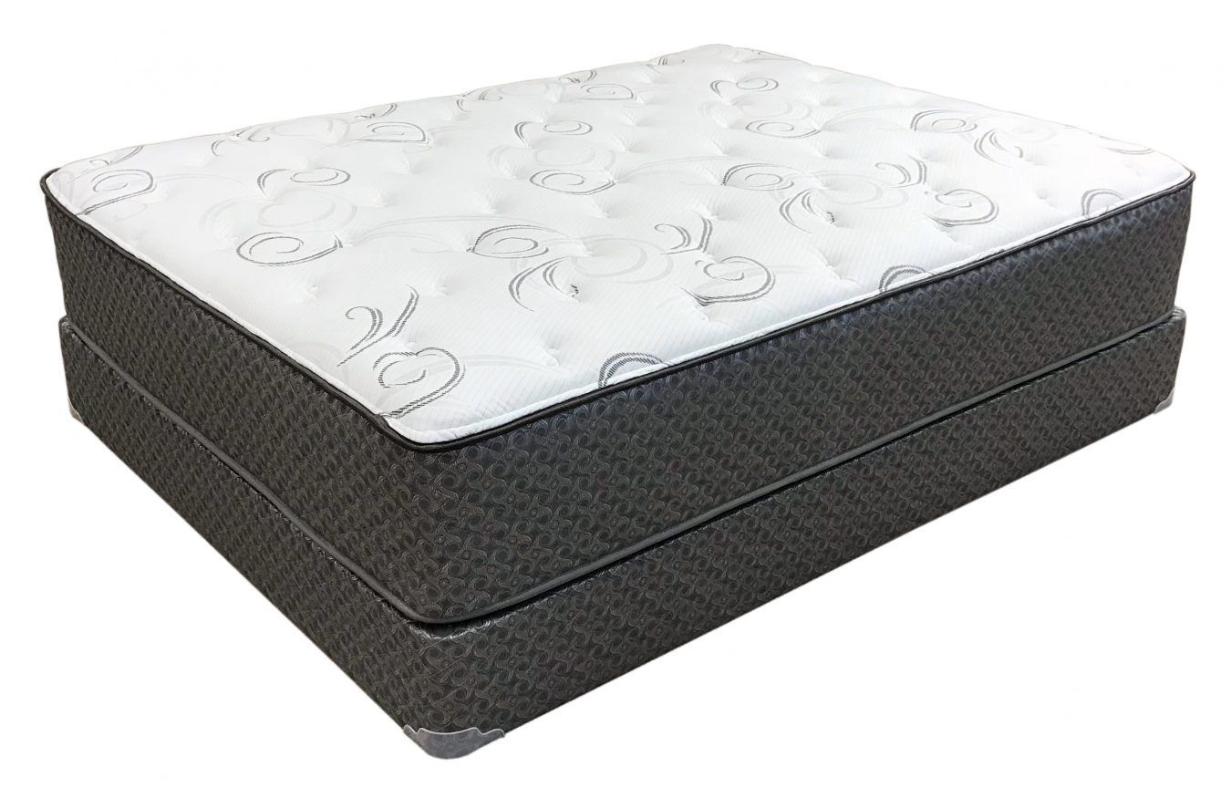 A white mattress with a patterned top surface rests on a dark gray upholstered box spring against a white background.