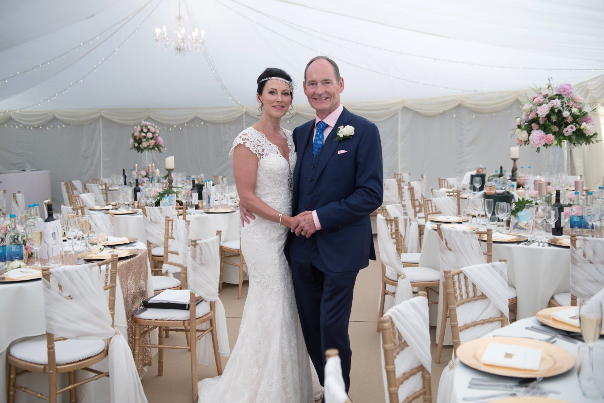 A bride and groom are posing for a picture in a tent.