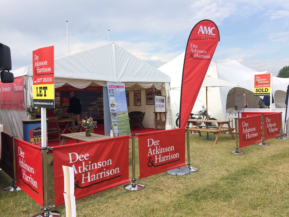 A dee atkinson & harrison tent is sitting in the middle of a field.