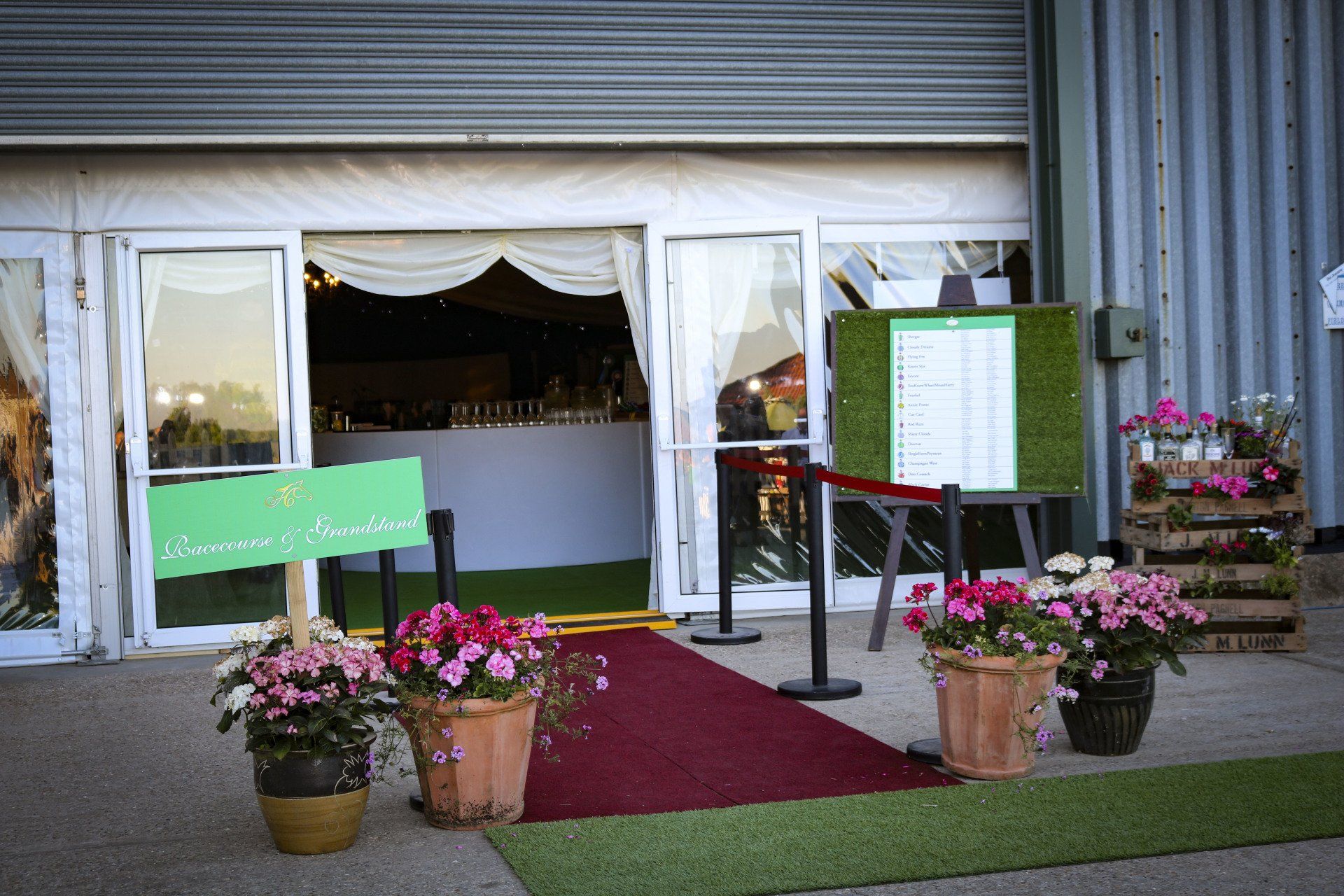 A red carpet is leading to a building with flowers in pots.