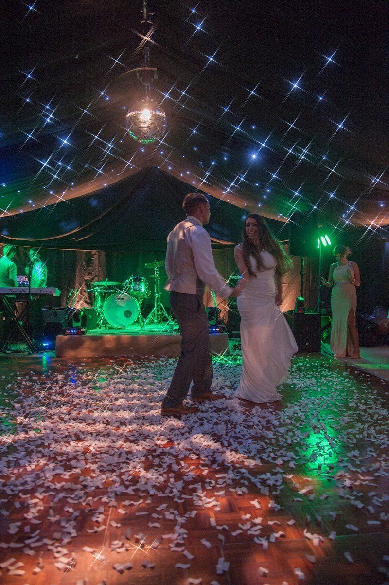 A bride and groom are dancing under a tent at a wedding reception.