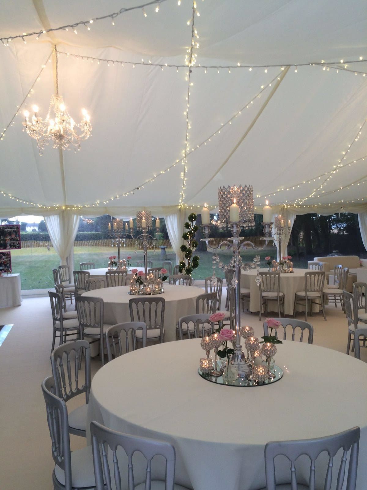 A large tent with tables and chairs and candles on them