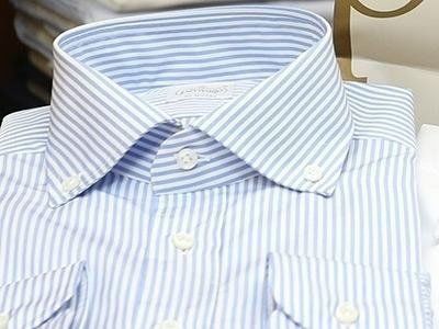 Camicia elegante a righe azzurre e bianche con colletto button-down, piegata ordinatamente.