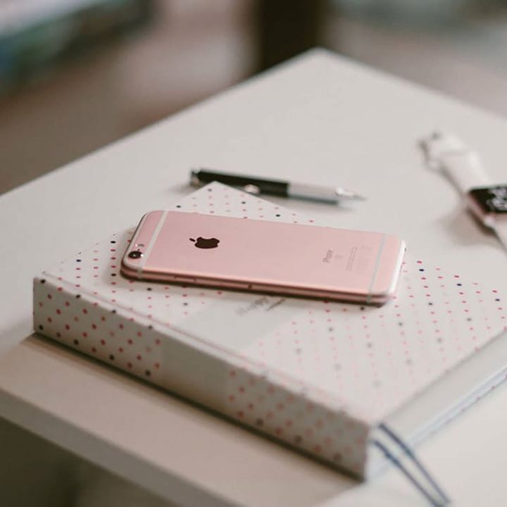 A pink iphone is sitting on top of a notebook