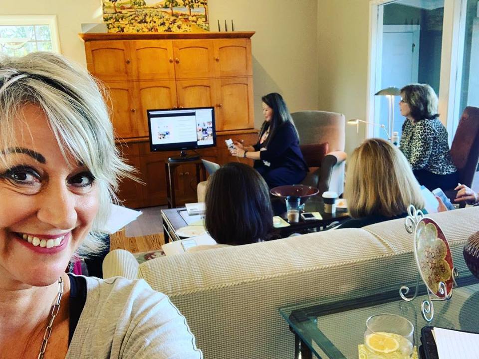 A group of women are sitting on a couch in a living room.