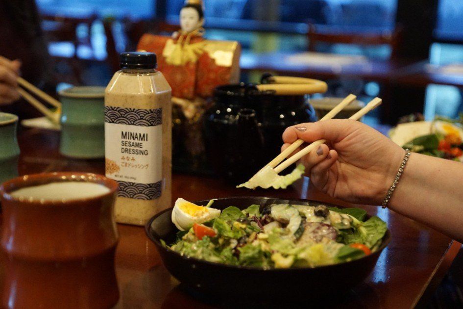 A person is eating a salad with chopsticks in a restaurant.