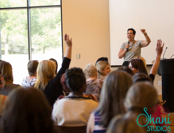 A group of people are raising their hands to answer a question during a presentation by shani studios