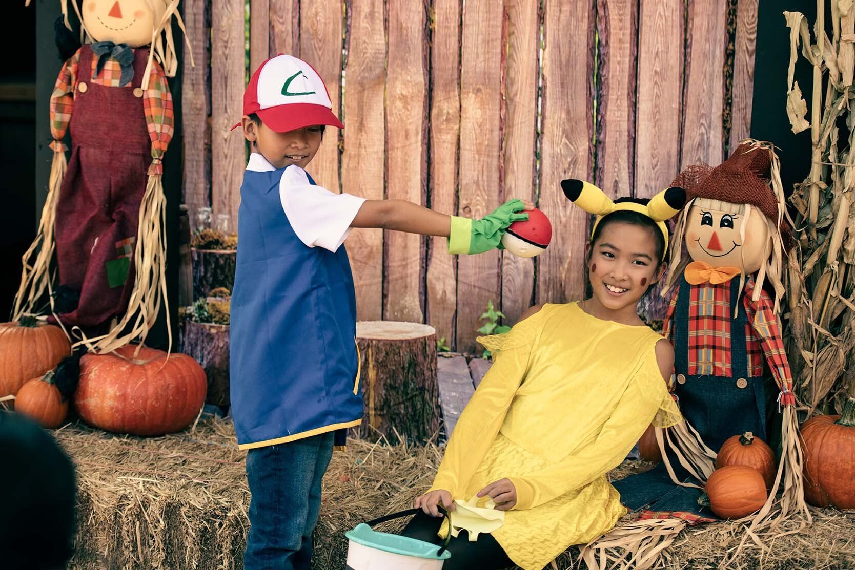 A boy in a pokemon costume is giving a girl a pokemon ball.