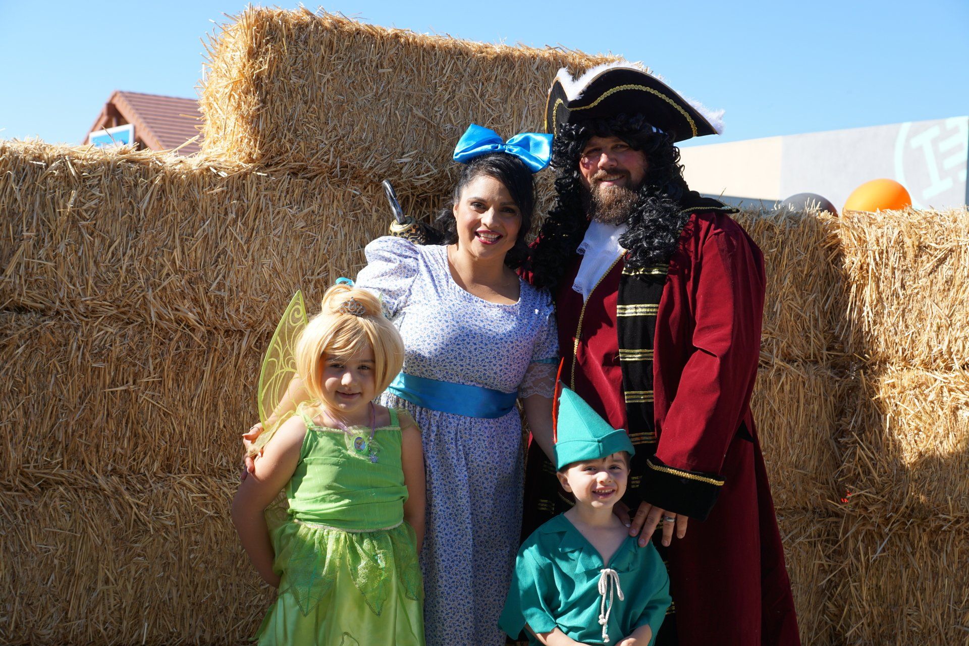 A family posing for a picture in front of hay bales