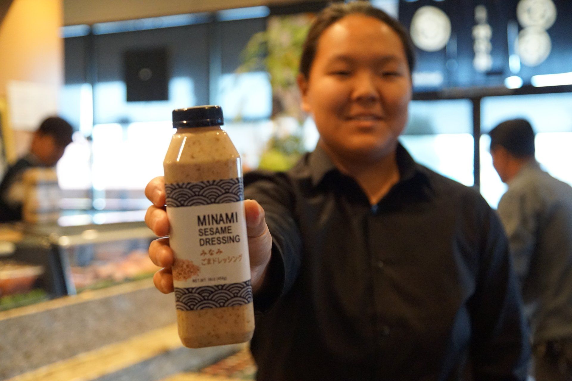 A woman is holding a bottle of vinaigrette in her hand