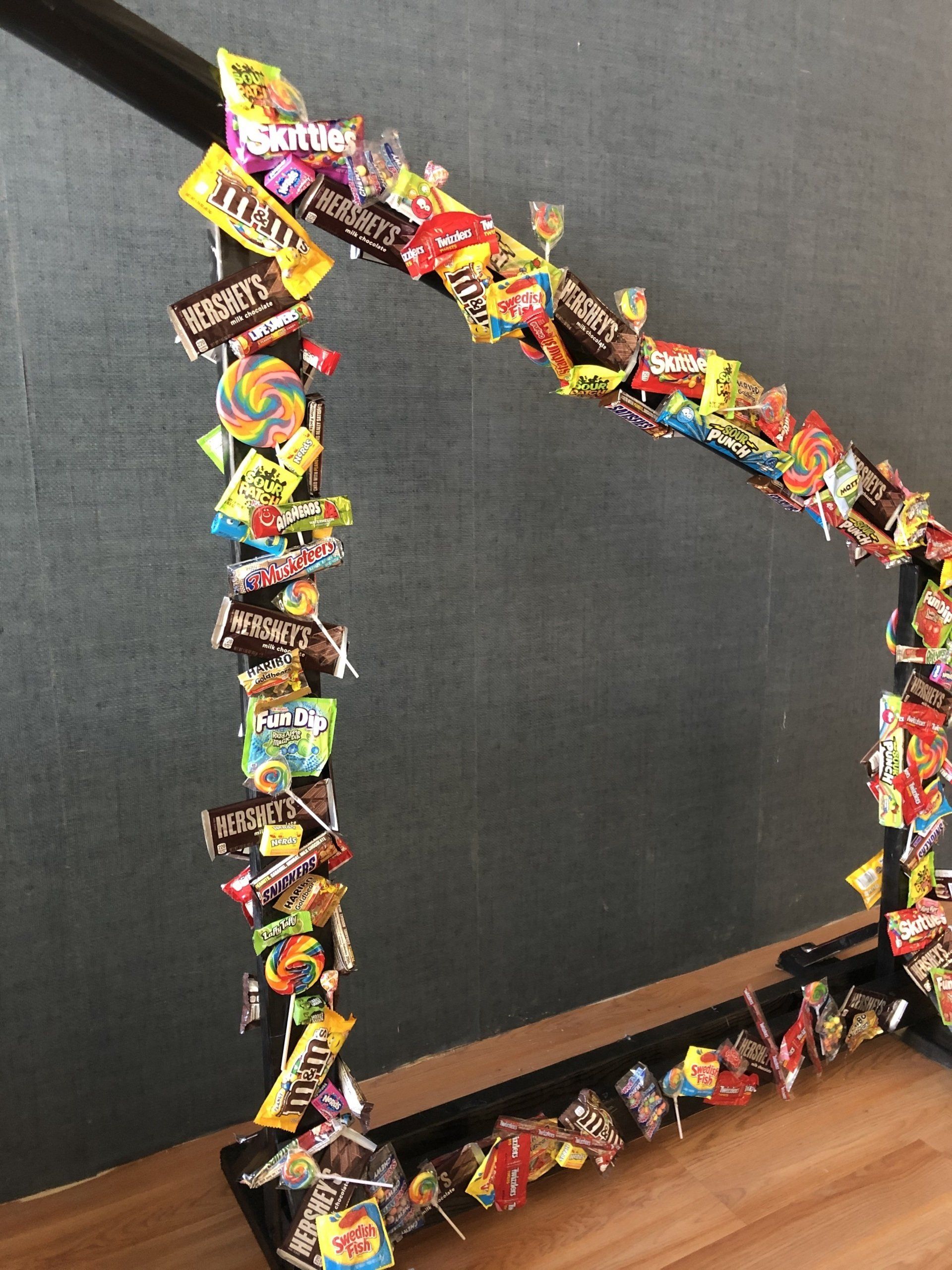 A picture frame filled with candy is sitting on a wooden floor.