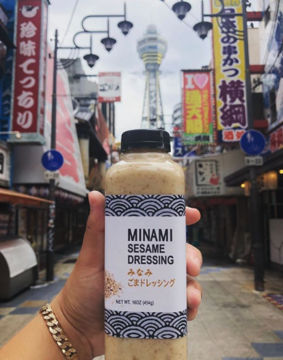 A person is holding a bottle of minami sesame dressing
