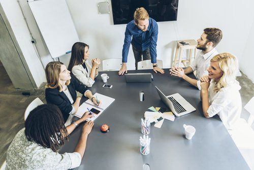 A group of people are sitting around a table having a meeting.
