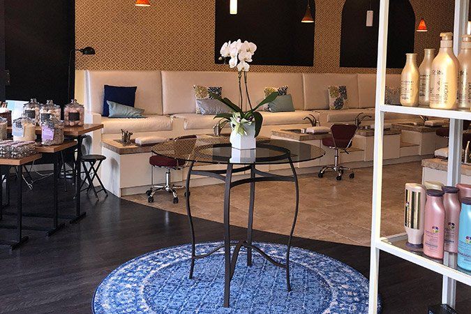 A salon with a blue rug and a table with a vase of flowers on it.