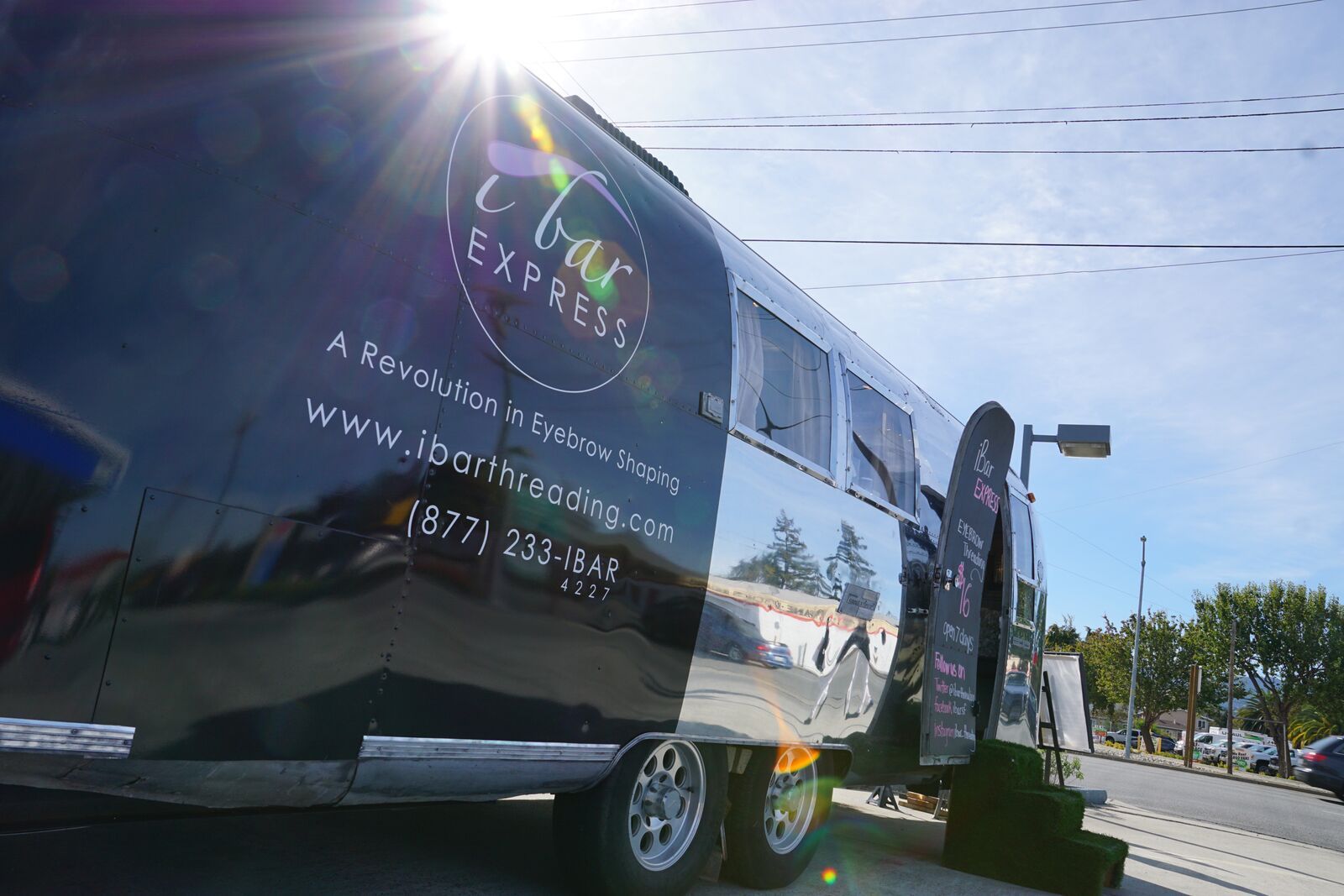 A black airstream trailer is parked on the side of the road.