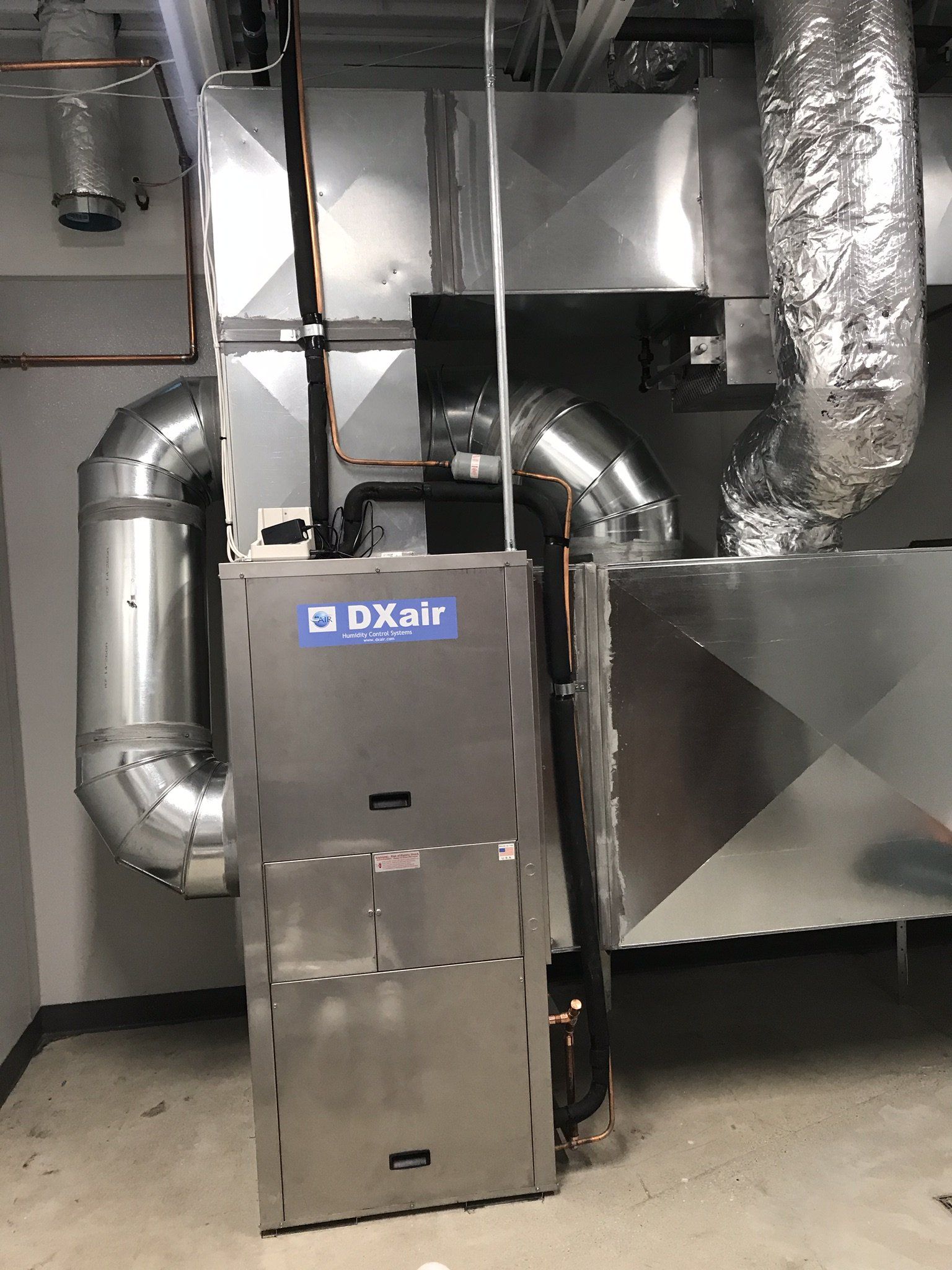 a stainless steel air conditioner is sitting in a room next to a wall .