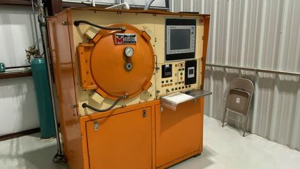 A large orange machine is sitting in a room next to a chair.