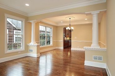 An empty living room with hardwood floors and a chandelier hanging from the ceiling.