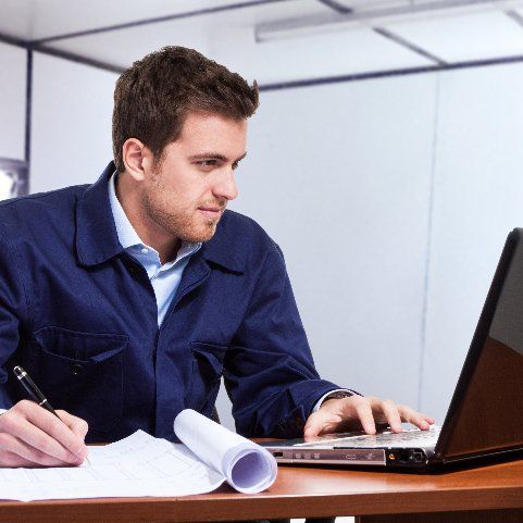 A man in a blue jacket is working on a laptop