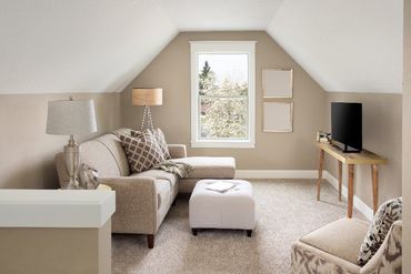 A living room with a couch , chair , ottoman and television.