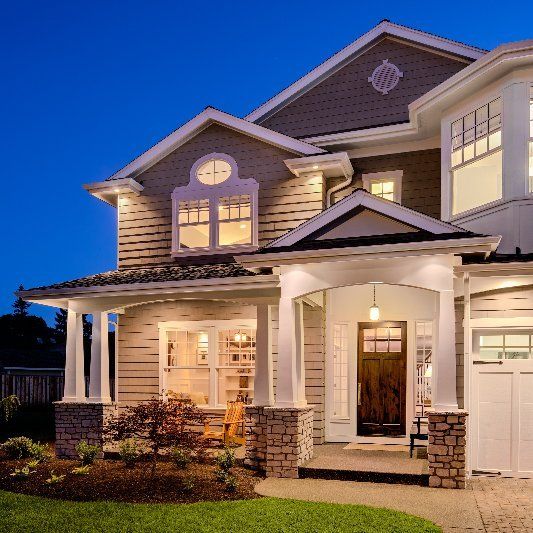 A large house with a clock on the roof is lit up at night