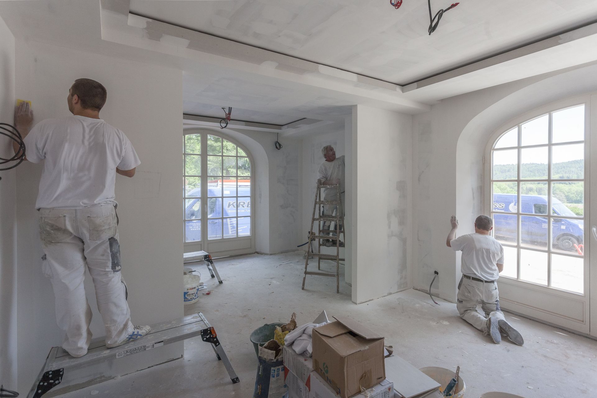A group of men are working on a wall in a room.