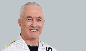 Smiling man in a white gi against a gray background