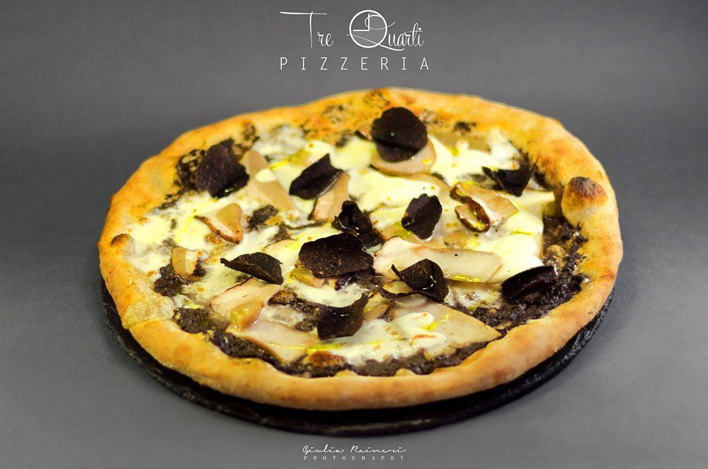 Pizza con funghi, tartufi e formaggio su un piatto scuro, con il logo 