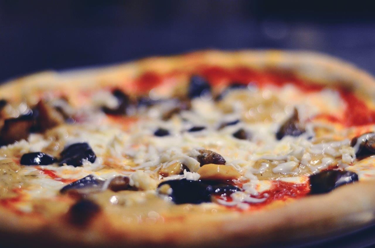 Primo piano di una pizza con funghi, formaggio e salsa di pomodoro.