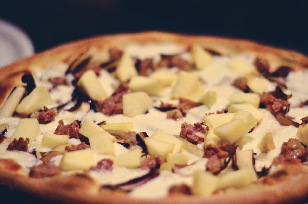 Pizza con pezzi di mela e salsiccia.